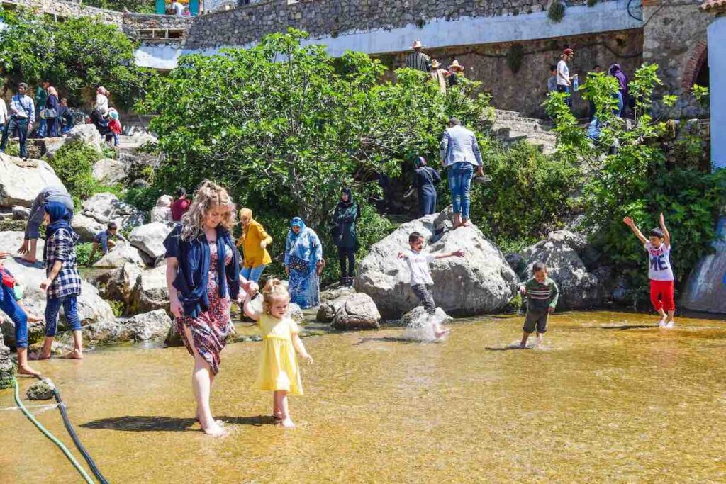 Mother and daughter holding hands and wading in Ras El Maa Spring, Morocco