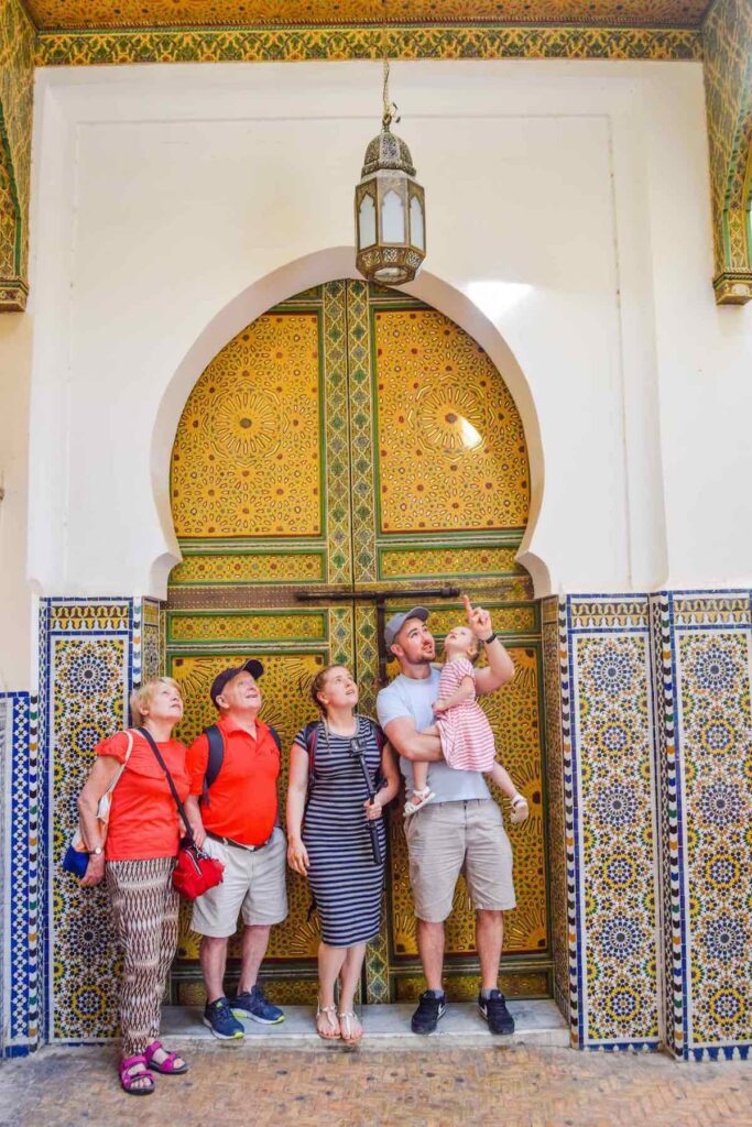 Fes with kids, a family stand outside a Mosque admiring the beautiful colourful tiles