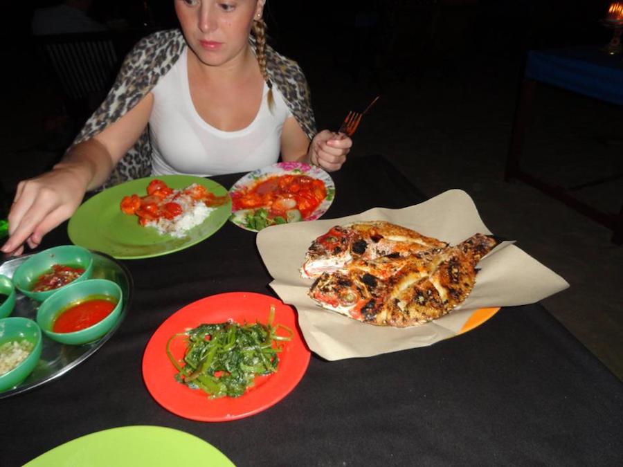 Lady enjoys sea food at Jimbaran beach restaurant