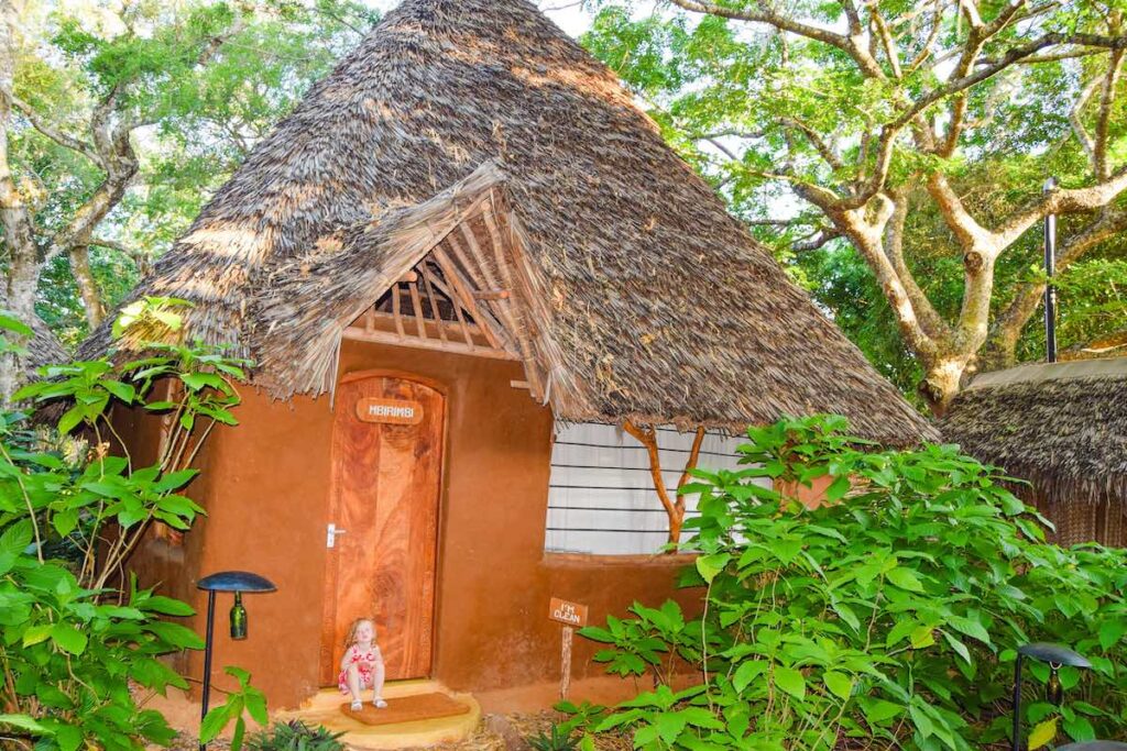 A young girl sits outside a wooden banda at Distant Relatives Ecolodge & Backpackers