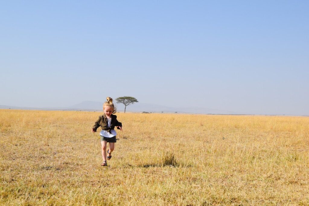 Child runs in the Masai Mara on safari