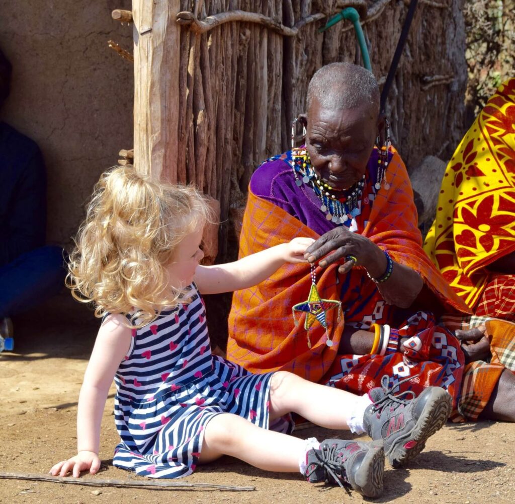 A child and Maasai elder look at jewellery together