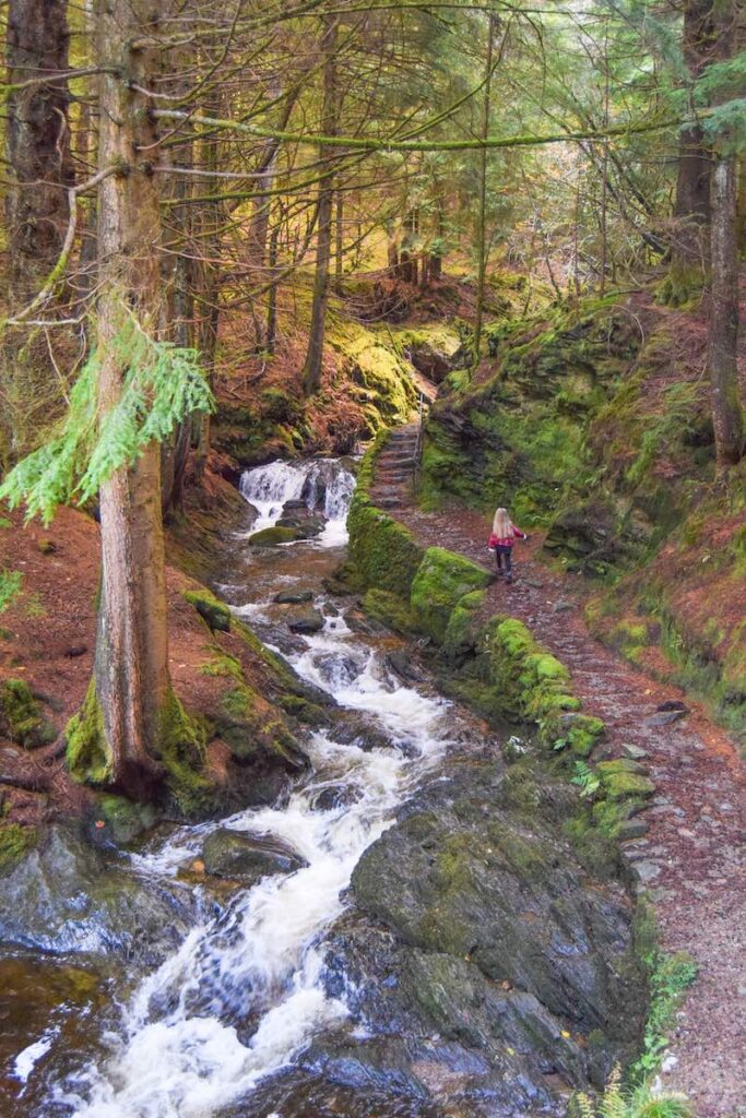 Young girl walks through Puck’s Glen, next to a stream