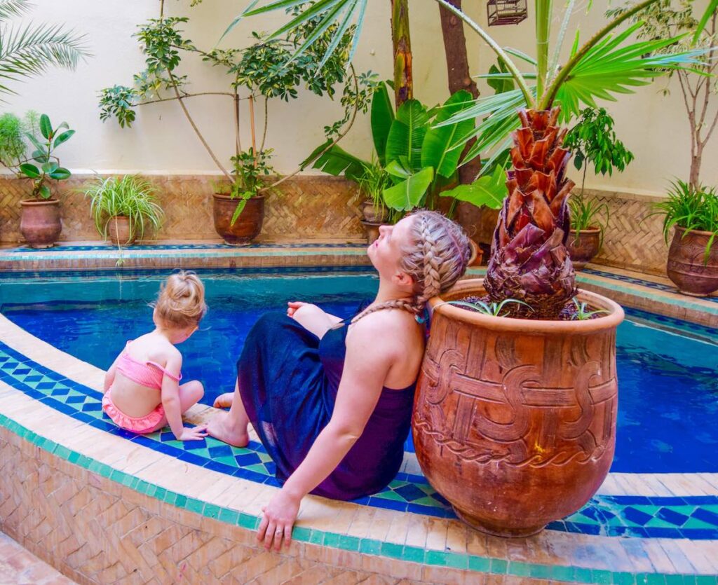 Mother and young daughter sit relaxing around the pool at Riad La Cle De Fes pool Morocco accommodation