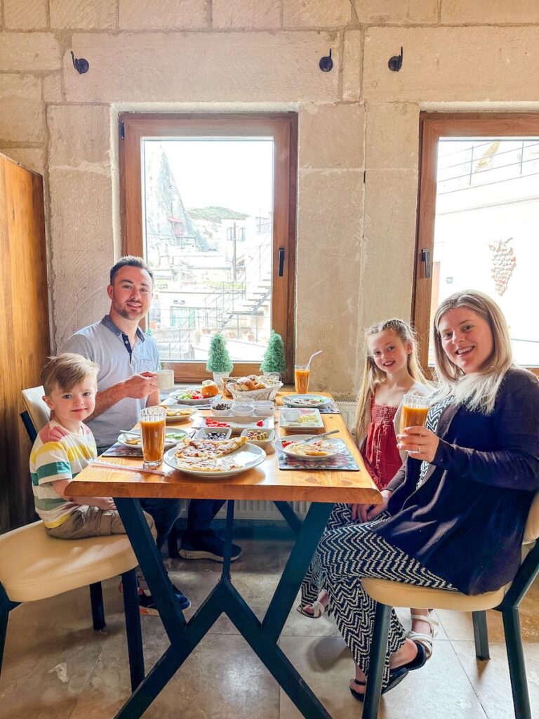 Family of 4 sit around a table at Salkim Cave House eating breakfast