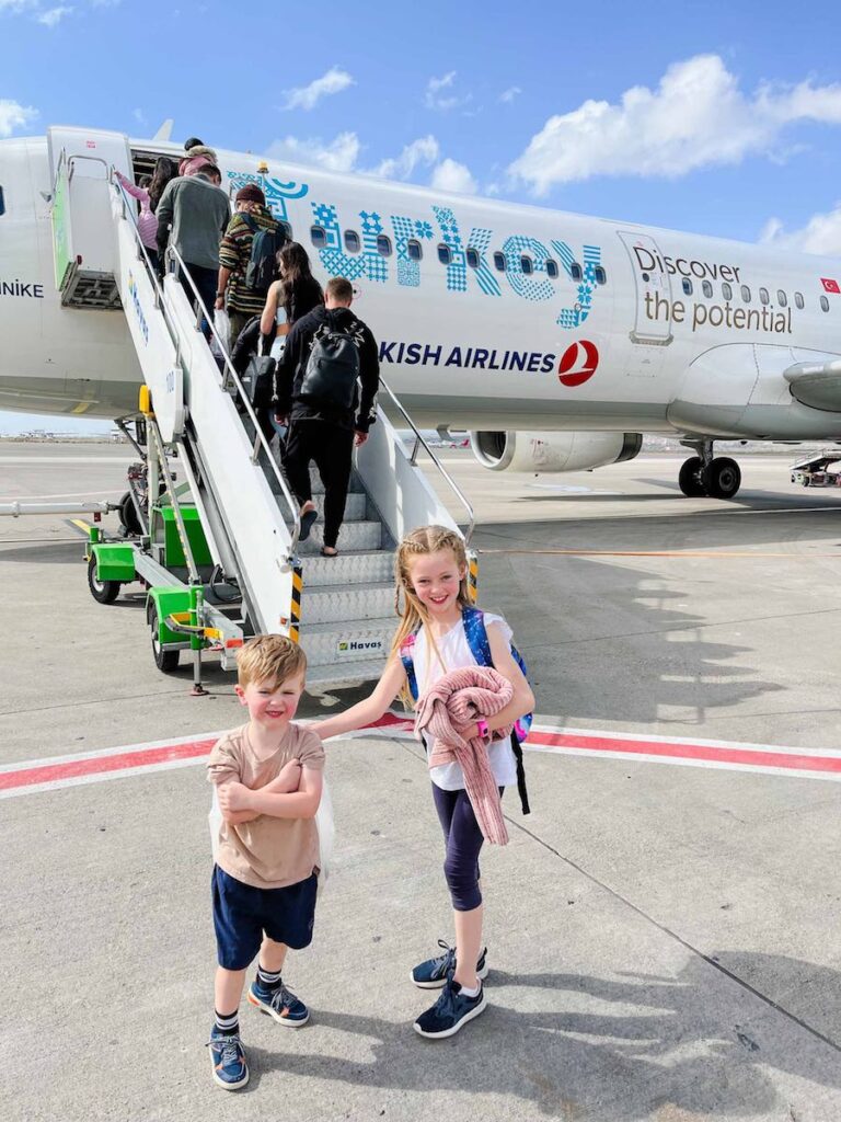 Young siblings stand in front of Turkish Airlines aeroplane