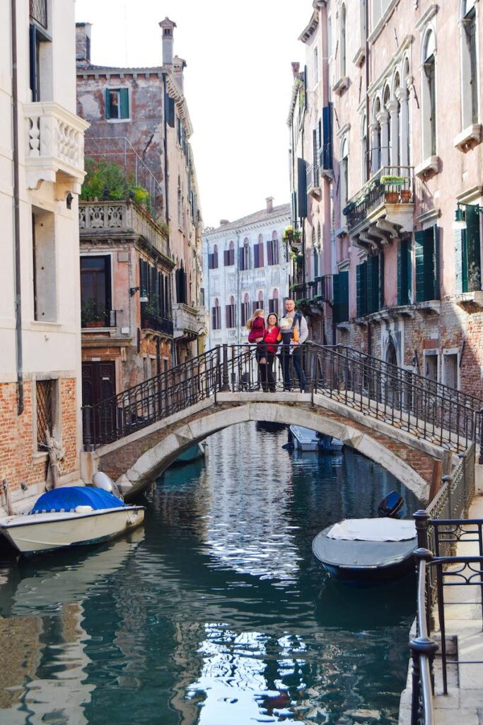 A family standing on a picturesque bridge over a Venice canal, enjoying the view.