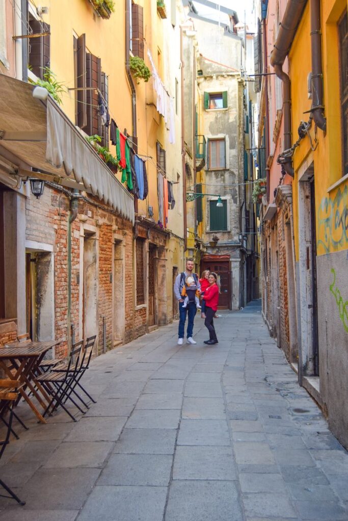 Family standing together on a quiet Venetian street surrounded by historic buildings.