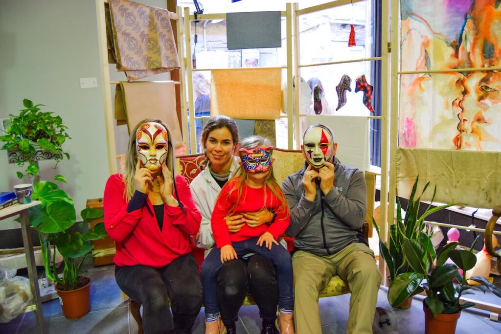 Family painting and decorating Venetian masks at a mask workshop