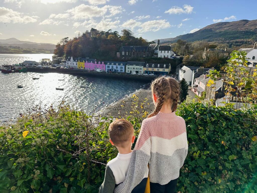 Kids exploring Portree harbour with its colourful houses on the Isle of Skye, perfect for family travel.
