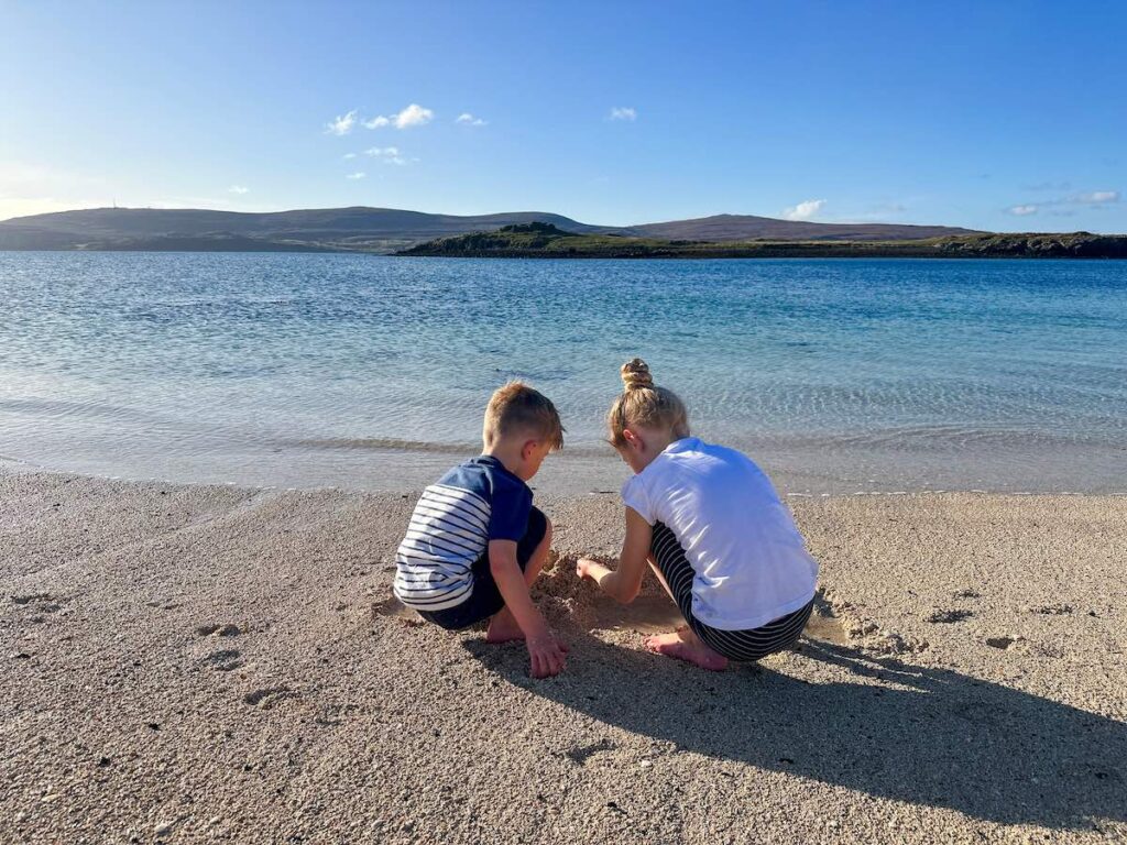 Children playing barefoot in the sand on Coral Beach, Isle of Skye, Scotland.