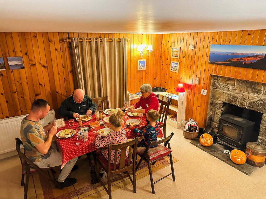 Family enjoying a meal together around the table in a self-catering cottage on the Isle of Skye.