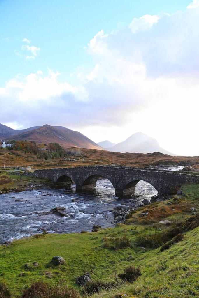 Sligachan Old Bridge on the Isle of Skye, Scotland, with river and mountains in the background.