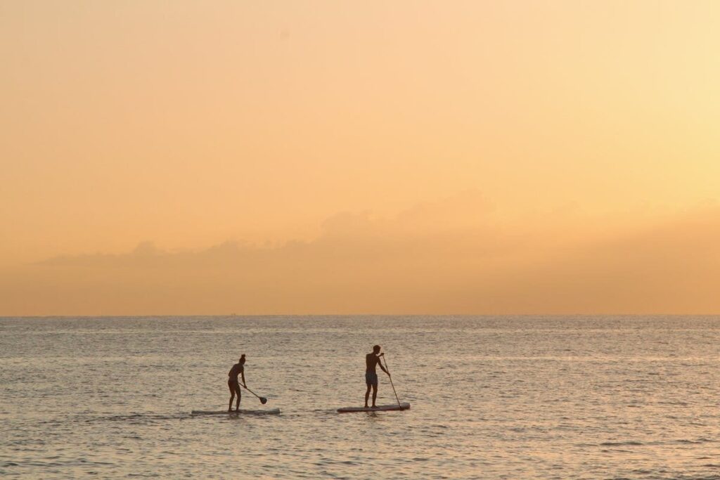Person paddle boarding on the clear blue waters of the Amalfi Coast in Italy.